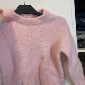 Rosa stickad tröja - Mysig rosa stickad tröja med rund hals och långa ärmar. Perfekt för kyliga dagar med sin mjuka och fluffiga textur. Enkelt att matcha med olika outfits. Är kanske liten i storlek så skulle säga s-xs 