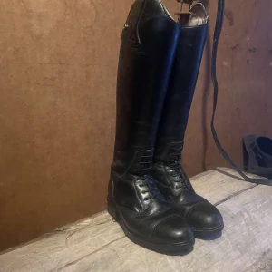 Svarta ridstövlar i skinn - Säljer mina gamla ridstövlar då dom inte passar så bra längre.   Dom är ifrån Mountain Horse. I storlek 35.   Ena knappen högst upp på ena ridstöveln vill inte stänga. Går säkert att fixa!   400kr eller bud