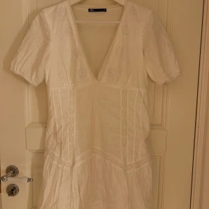 Vit klänning från Zara - Säljer en söt vit klänning från Zara med v-ringning och korta ärmar. 
