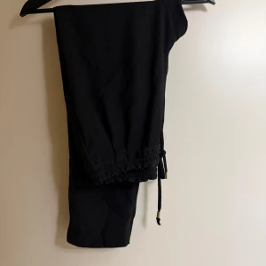 Svarta byxor från Zara Basic - Snygga svarta byxor från Zara Basic med elastisk midja och dragsko. Perfekta för en avslappnad stil. Tillverkade i ett mjukt material som ger en bekväm passform.
