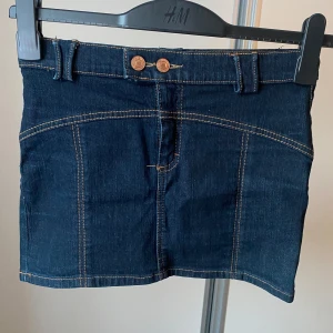 Mörkblå vintage retro jeanskjol - Cool vintage mörkblå jeanskjol med dubbla knappar och bälteshällor. Kjolen har dekorativa snygga sömmar och har inga slitage. Köpt second hand. Måtten finns på bilden men för att förtydliga; Bild 3 längden uppifrån och ner: Ca 30 cm. Bild 4 Midjemått rakt över: Ca 35 cm. Kjolen är i storlek ”6”, skulle säga att det är xxs/xs. Skriv gärna om funderingar uppstår/ behövs mer bilder eller mått❣️