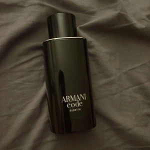 Armani Code Parfum - Elegant och stilren flaska i svart med texten 'Armani Code Parfum'. Perfekt för den som söker en sofistikerad doftupplevelse.