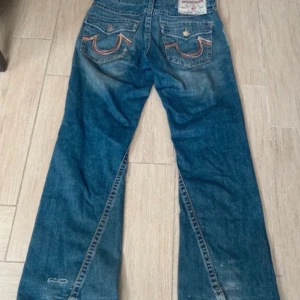 Trueys  - Jättefina True Religion jeans som tyvärr är för stora på mig. Tyvärr även lite slitna nertill. Storlek W34 Innerbenslängd: 81 cm. Ytterbenslängd: 110 cm. Midjemått mätt rakt över: 48 cm.  