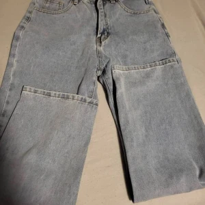 Ljusblå jeans - Säljer ett par ljusblå jeans i klassisk stil. De har en normal passform och är perfekta för vardagsbruk. Jeansen är i bra skick och har en knapp och dragkedja framtill. Perfekta för både vår och sommar! Aldrig använda