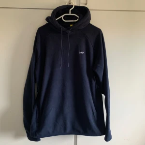 Mörkblå fleece hoodie från MP - Säljer en supermjuk och bekväm mörkblå fleece hoodie från MP. Perfekt för lata dagar eller när du bara vill mysa. Den har en klassisk passform med långa ärmar och en praktisk huva med dragsko. Perfekt för höst och vinter!