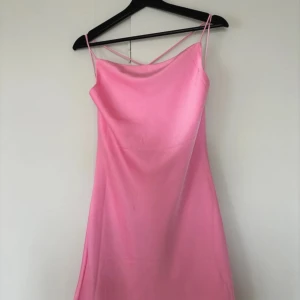 Rosa axelbandslös klänning - Säljer en superfin rosa klänning med smala axelband. Perfekt för sommarens fester eller en mysig kväll ute. Klänningen har en enkel och elegant design som gör den lätt att matcha med olika accessoarer.