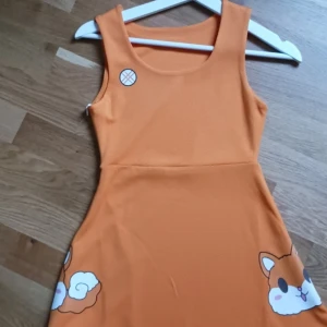 Inquisitormaster klänning - Superfin orange klänning. Den är ärmlös och perfekt för sommardagar. Klänningen har en enkel och lekfull design som passar både vardag och festliga tillfällen. Materialet känns mjukt och bekvämt. Köpt från inquisitormasters butik men säljer då den är för liten och jag kollar inte på henne längre.