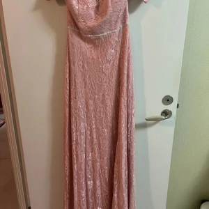 Rosa spetsklänning från Moments New York - Säljer en superfin rosa långklänning från Moments New York. Klänningen är i spets och har en elegant offshoulder-design. Perfekt för sommarens fester eller en romantisk bal. Den har en dragkedja i ryggen för enkel påklädning. 🌸