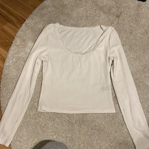 Vit ribbad topp från Shein - Säljer en söt vit ribbad topp från Shein i storlek XS. Toppen har långa ärmar och en fin spetsdetalj runt halsringningen. Perfekt för både vardag och festliga tillfällen. Superbekväm och lätt att matcha med olika outfits!