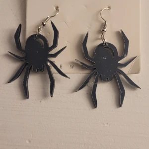  Helt nya Svarta spindelörhängen - Coola svarta örhängen i form av spindlar, perfekta för en unik och edgy stil. De är lätta och bekväma att bära, med en krok för enkel användning. Passar perfekt till Halloween eller för att ge din outfit en extra touch av mystik.