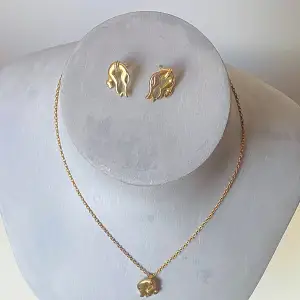 Elegant smyckeset med  örhängen och matchande halsband. Örhängena har en stilren, vågig design och halsbandet har ett hänge i form av kattdjur . Perfekt för att ge en touch av lyx till din outfit.