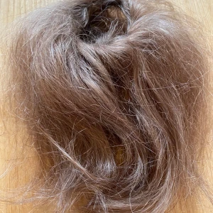 Brun hårtofs - Säljer en brun hårtofs som sitter på en snodd. Perfekt för att ge extra volym till din frisyr eller för att använda som en håraccessoar. Färgen är en naturlig brun nyans. Använt skick.