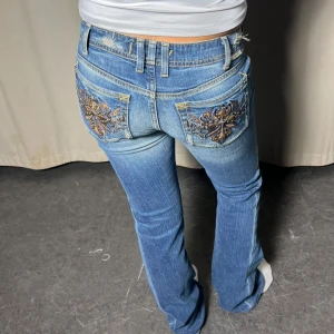 Lågmidjade jeans - Lågmidjade blåa bootcut jeans med snygg tvätt och unika fickor!! ✨  Innerbenslängd: 79cm Midja: 27x2   Modellen är 163 cm lång 