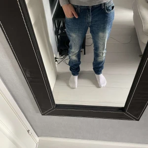 Lee jeans - Säljer ett par snygga blå jeansbyxor i slim fit. De har en klassisk femficksdesign och en lätt slitning på framsidan för en cool look. Perfekta för både vardag och fest! Storlek 31