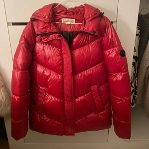 Röd dunjacka från Michael Kors - Snygg röd dunjacka från Michael Kors, som är helt oanvänd. Nypris 5000 kr men säljer den för 2500 kr. Perfekt för kalla dagar när du vill hålla dig varm och stilren.