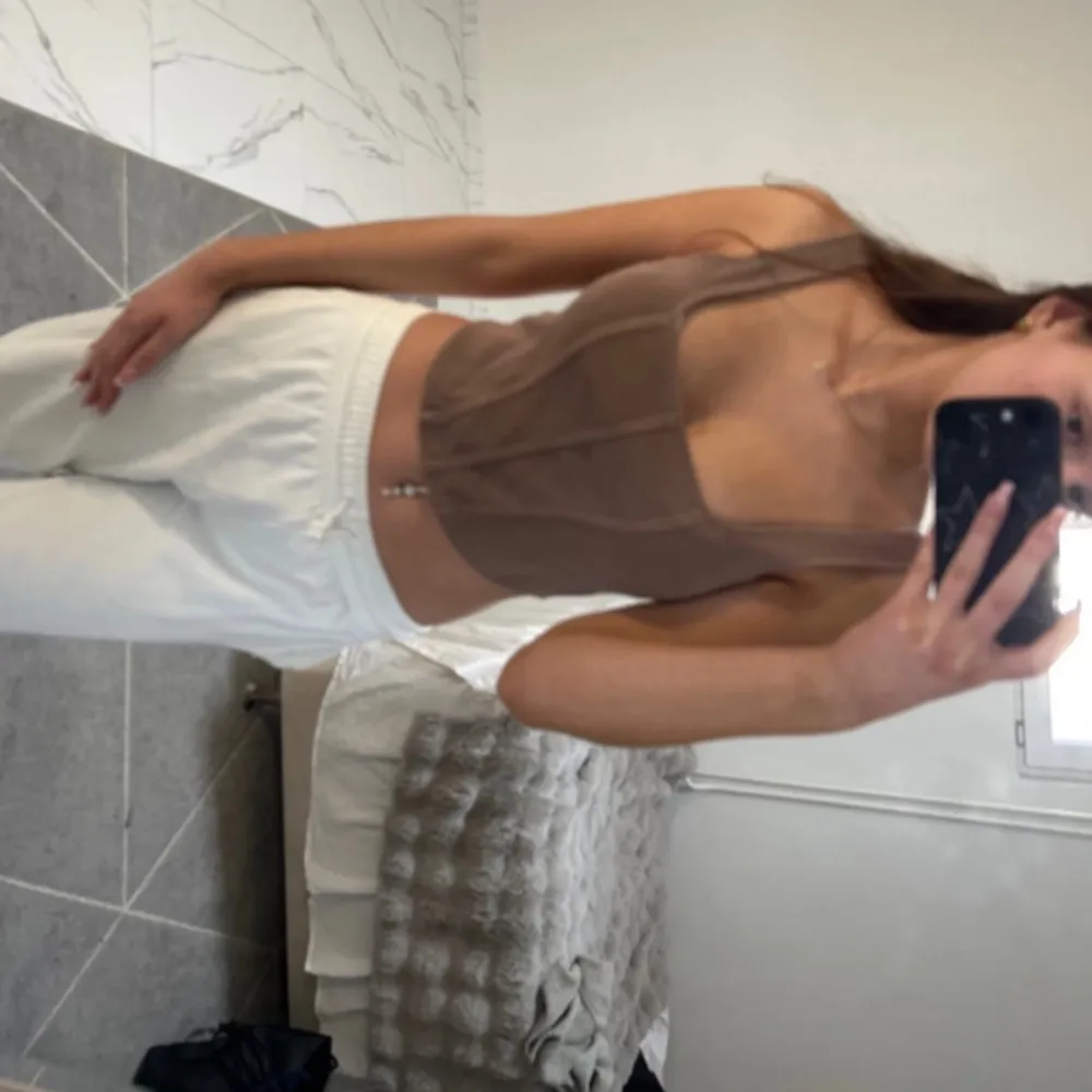 Säljer en stilren beige ribbad linnetopp från H&M. Toppen har breda axelband och en figurnära passform som ger en snygg siluett. Perfekt för att matcha med både jeans och kjol. Hör av dig vid intresse!. Yläosat.