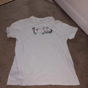 Vit Levi's t-shirt - Vit t-shirt från Levi's med ett färgglatt blommigt tryck på bröstet. 100% bomull.
