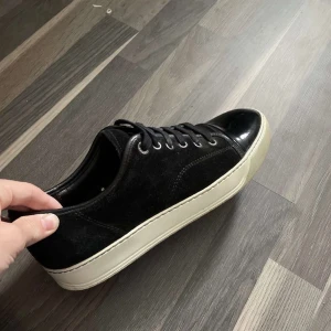 Bytes - Snygga svarta sneakers med vit sula och snörning. Skorna har en blank tådel och är tillverkade i mocka. Perfekta för en stilren look.