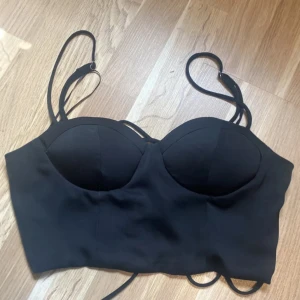 Topp - Säljer denna svarta toppen som har korsade snörningar vid ryggen. Köpte den från Gina men använder inte. Den är i storlek M. 💓💓🙏