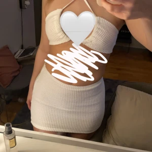 Vit ribbad klänning - Snygg vit ribbat sett med en tight passform. Toppen är ärmlös och har en kort längd, perfekt för sommarens varma dagar. Den har en enkel och stilren design med smala axelband. Aldrig använd 