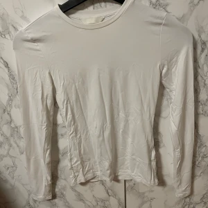 Mikrofiber Vit långärmad tröja från H&M - Säljer en stilren vit långärmad tröja från H&M. Perfekt basplagg för alla tillfällen. Tröjan har en enkel design med rund hals och är tillverkad i ett mjukt material.