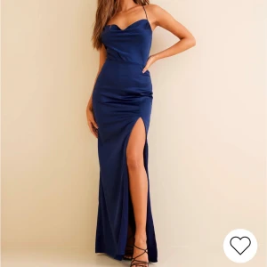 Marinblå långklänning i satin - Elegant marinblå maxiklänning i satin med slits vid sidan, smala axelband och en vacker draperad halsringning. Endast använd en gång,pris kan diskuteras vid snabb affär! Bra skick förutom en liten fläck som knapp syns förutom om man tar bild med flash eller lyser med ficklampa, går säkert bort i tvätt!