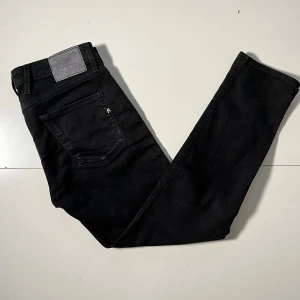 Svarta jeans från Replay - Snygga svarta jeans från Replay med en klassisk femficksdesign. De har en dragkedja och knapp framtill samt Replay-logga vid fickan. Perfekta för en stilren look. Modellen är anbass och storleken är W32 L30. Priset är inte fast kan diskuteras vid snabb affär