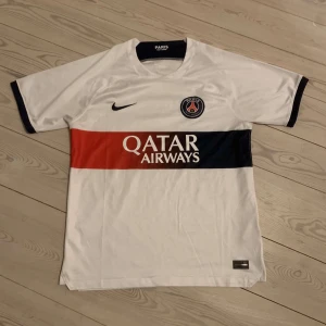 Vit PSG fotbollströja från Nike - Säljer en vit PSG fotbollströja. Tröjans kvalitet är bra och endast använda nån enstaka gång. Tröjan är ej äkta därav priset! OBS tröjan är stor i storleken!