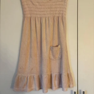Ljusrosa frottéklänning från Juicy Couture - Rosa klänning med ”handduksmaterial” från juicy couture. lite stor för mig så skulle säga att den passar M/L. finns två små fläckar som kan man se på bild 1.