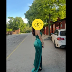 Grön axelbandslös långklänning, baddie - Snygg grön axelbandslös långklänning i satin med en elegant slits på sidan. Perfekt för en glamorös kväll med sin glänsande finish och figurnära passform. Använt 1 gång riktig baddie fick massa komplimanger när jag hade på mig den, 