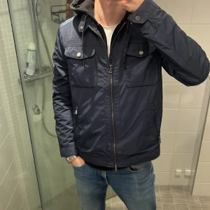 Mörkblå vår jacka - Vi säljer nu en sjukt snygg mörkblå windbreaker med dragkedja och knappar. Jackan är i storlek L men sitter bättre för M. Jackan har långa ärmar och flera praktiska fickor med lock framtill. Jackan har i mycket bra skick den ändå defekten är att en dragkedja på en ficka har hängt sig men går lätt att byta! Perfekt för vårdagar och sommarkvällar! Vårt pris 400kr priset är absolut inte hugget i sten. Dm för frågor eller bilder🤗
