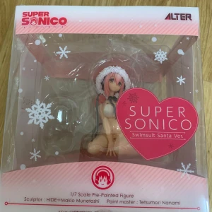 Super Sonico Swimsuit Santa Ver. Figur - Super Sonico-figur i Swimsuit Santa-version från Alter. Denna 1/7 skala förmålade figur är skapad av HIDE och Makio Munetoshi, med Tetsumori Nanami som målningsmästare. Perfekt för samlare av animefigurer. Köpt från AmiAmi