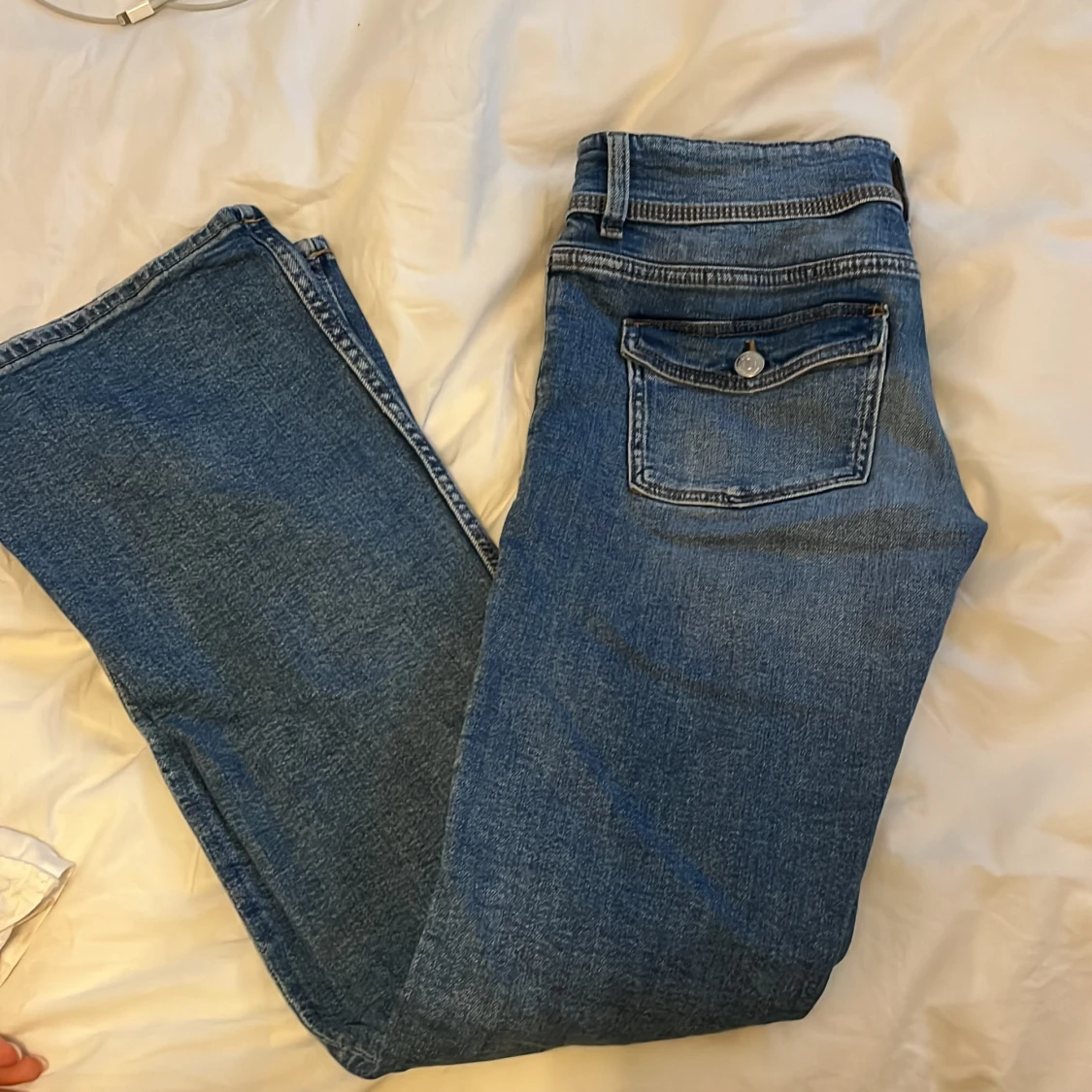 Blå bootcut jeans med knapp fickor där bak