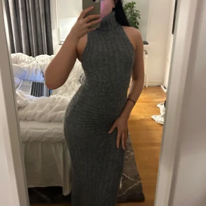 Adoore Montreux dress st 32 - Snygg grå ribbad långklänning med polokrage och ärmlös design. Perfekt för en stilren look. Klänningen har en tight passform som framhäver figuren.