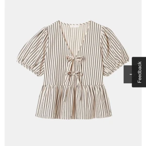 Randig blus med knytband - Säljer en söt randig blus med puffiga kortärmar och v-ringning. Blusen har knytband framtill och en lätt volang nedtill. Perfekt för en stilren look. Kontakta för egna bilder 