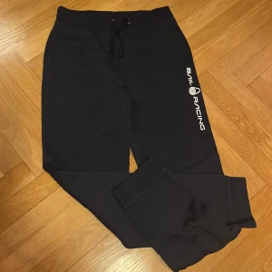 Marinblå mjukis set från Sail Racing - Snygga marinblåa mjukisbyxoroch hoodie från Sail Racing. Byxorna har en bekväm passform med resår och snörning i midjan. Perfekta för en avslappnad stil. Kläderna är i mycket bra skick!