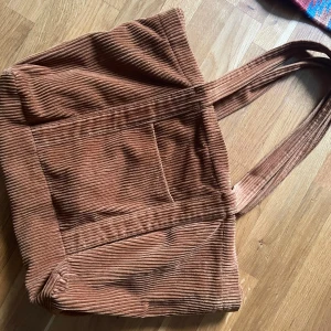 Brun manchesterväska från Zara - Säljer en snygg brun manchesterväska från Zara. Man får lätt plats med en laptop eller skolböcker! Den har ett fack på framsidan samt ett inuti och en dragkedja att stänga väskan med. 