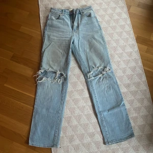Ljusa jeans med slitningar från Abrand Jeans - Snygga ljusblå jeans från Abrand Jeans med coola slitningar över knäna. De har en klassisk femficksdesign och en rak passform. Perfekta för en avslappnad stil.