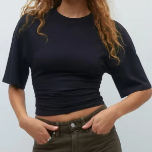 Svart croppad t-shirt - Snygg svart croppad t-shirt med korta ärmar. Perfekt för en avslappnad stil och kan enkelt matchas med olika outfits. Helt ny