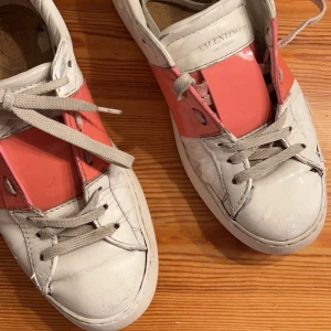 Valentino sneakers i vitt och rosa - Snygga Valentino sneakers i vitt med rosa detaljer. Skorna har snörning och en klassisk design som passar perfekt för en trendig look. Perfekta för dig som vill ha något unikt och stilrent. Har tagit ur sulan på bilderna men sätter såklart i den innan dom skickas och såklart äkta🥰