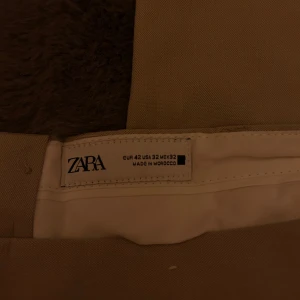 Beige byxor från Zara - Snygga beige byxor från Zara i en klassisk stil. De har en rak passform och är tillverkade i ett bekvämt material. Perfekta för en stilren look. Storlek EUR 42