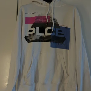 Vit hoodie med  tryck - Säljer en vit hoodie med ett coolt grafiskt tryck i rosa, blått och svart. Hoodien har en klassisk känguruficka och justerbar dragsko i huvan. 