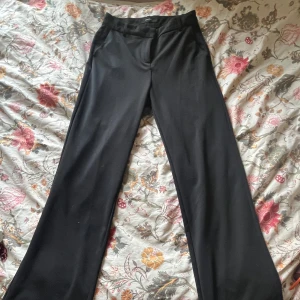 Svarta kostymbyxor från Vero Moda - Snygga svarta kostymbyxor från Vero Moda med en klassisk design. Byxorna har en rak passform och är högmidjade. Perfekt basplagg.