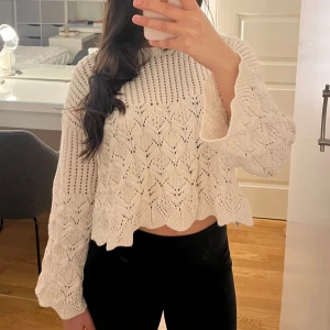 Vit stickad tröja från zara - Säljer en vit stickad tröja med ett vackert mönster och croppad design. Tröjan har långa ärmar och en rund halsringning, perfekt för en stilren look. Passar bra till både jeans och kjol. Perfekt för kyligare dagar!