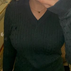 Ralph Lauren tröja  - Snygg svart ribbad tröja med v-ringning. Perfekt för en stilren look. Tröjan har långa ärmar och en figurnära passform. Polo 