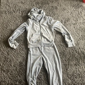 Ljusblå  hoodie och byxor från Gina Tricot - Säljer en ljusblåhoodie med dragkedja och matchande byxor från Gina Tricot. Hoodien har en praktisk ficka framtill och en bekväm huva. Perfekt för en avslappnad stil. 🩶