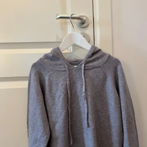 Merino hoodie - Säljer en stilren grå merinoulls hoodie med långa ärmar och justerbar huva. Perfekt för en avslappnad look. Tröjan är oanvänd och har bara prövats 
