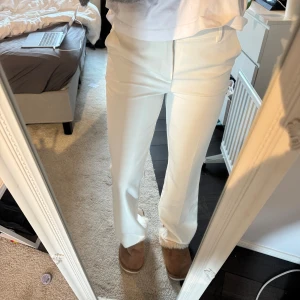Vita kostymbyxor - Snygga vita kostymbyxor med en klassisk rak passform. Byxorna har en stilren design med diskreta fickor och en smidig dragkedja framtill. Perfekta för en elegant look.