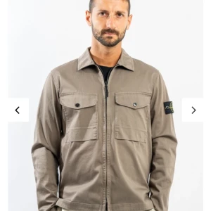Grå grön overshirt från Stone Island - Säljer en stilren ish grön overshirt från Stone Island med dragkedja. Köptes på Nk i Stockholm under september månad. Säljer overshirten då den blivit lite för liten, den är använd mindre än 10 ggr. Kvitto på sista bilden. Skicka meddelande för följande frågor.
