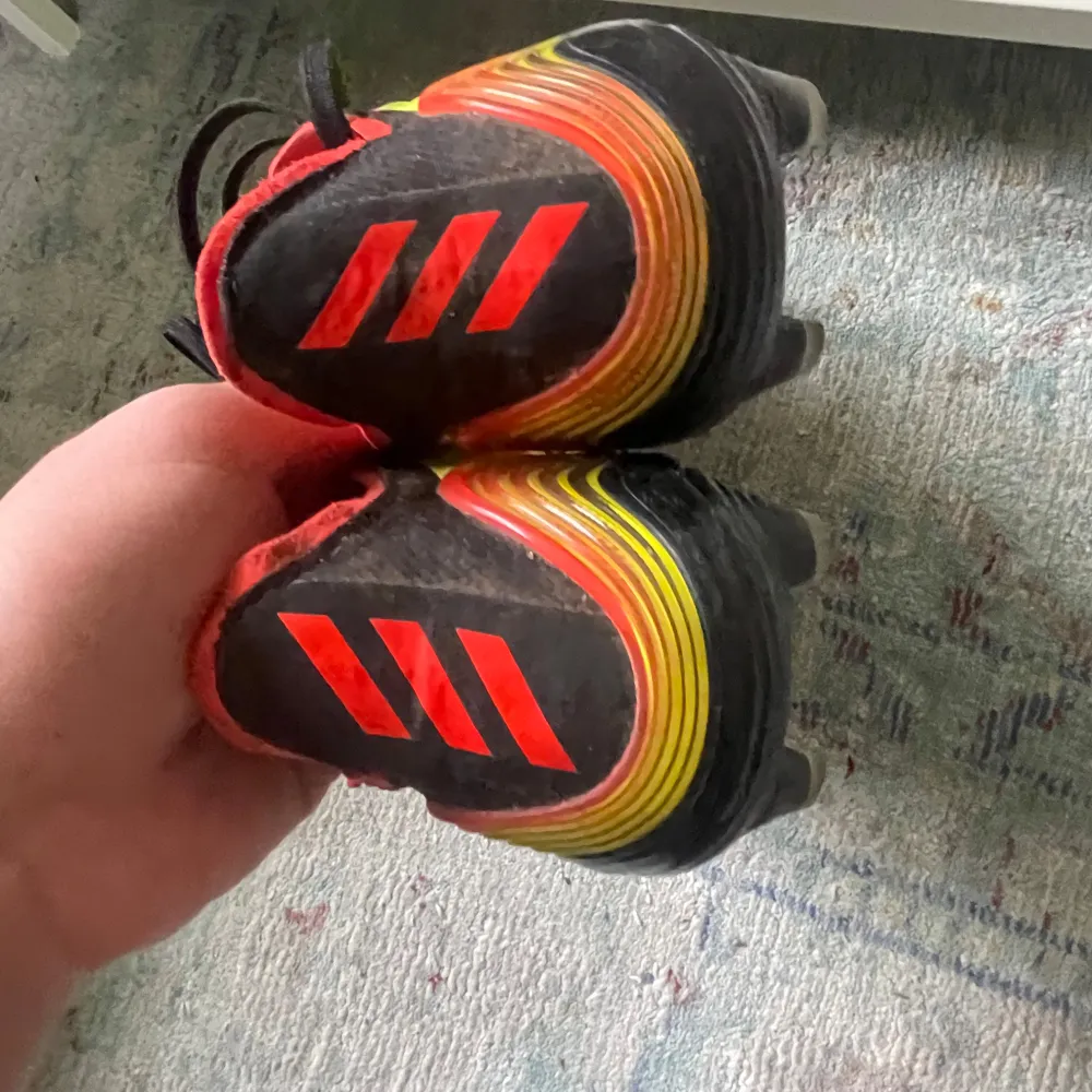 Snygga gula fotbollsskor från Adidas med svarta och röda detaljer. Perfekta för fotbollsspelare som vill sticka ut.. Kengät.
